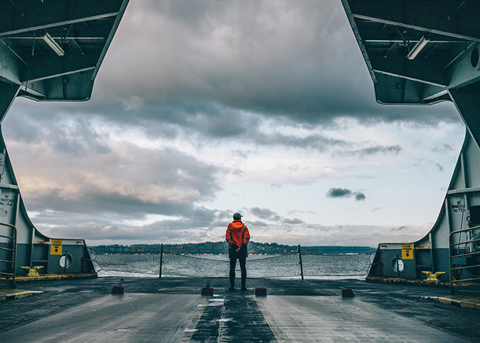 A ferry crew member looks out over the water from the lower deck.