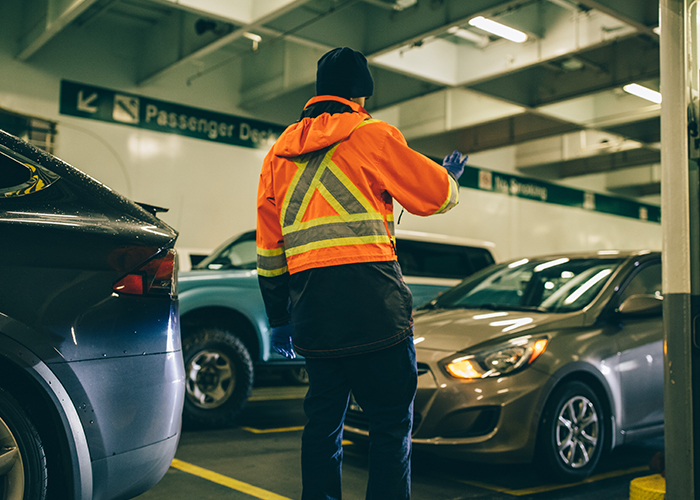 Ferry crew member gives visual instructions to a car passenger.